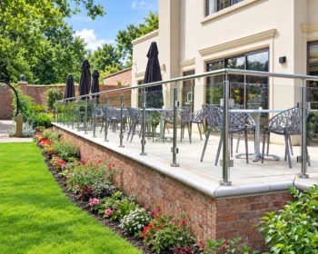 Stainless steel post and rail glass balustrade around a garden dining terrace